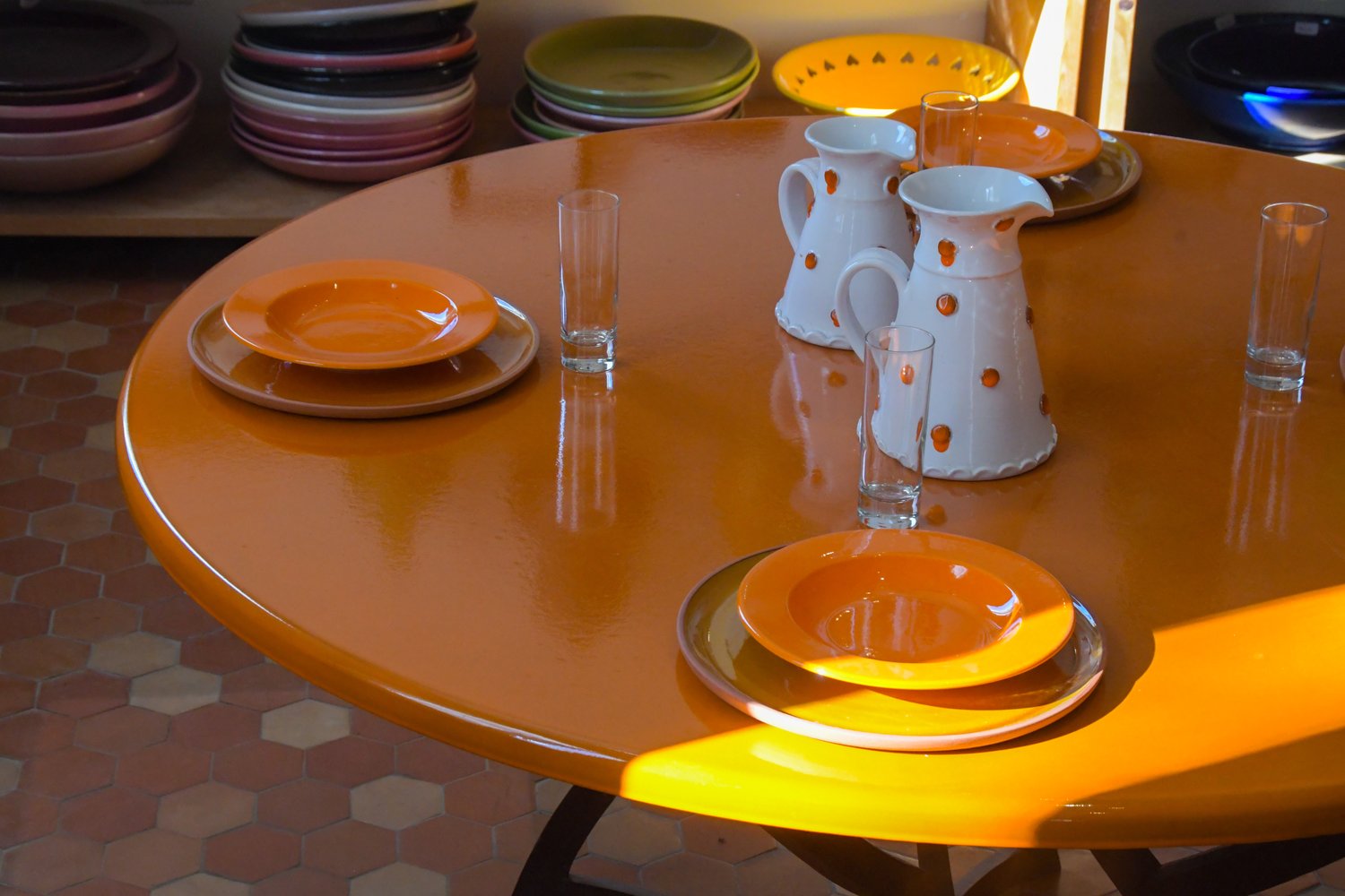 Table en lave émaillée orange dressée avec assiettes et pichets en céramique