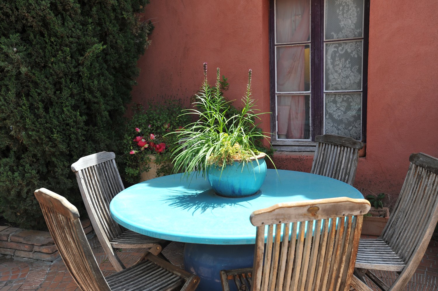 Table ronde en lave émaillée turquoise sur une terrasse fleurie